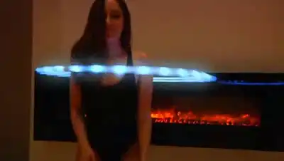 Сексуальная девушка со светящимся гимнастическим обручем показывает класс