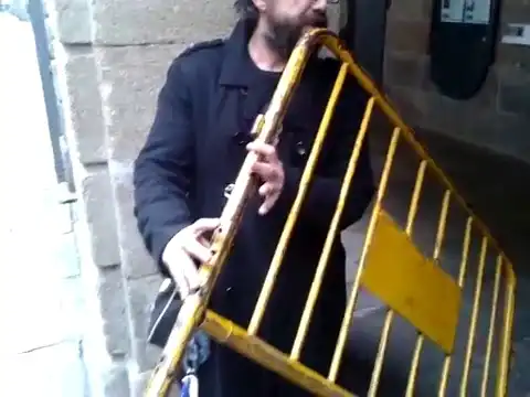 Уличный музыкант, который играет на спинке от кровати, как на флейте